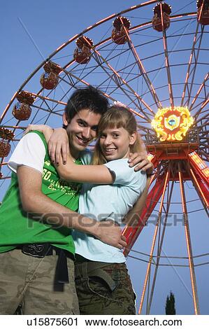 Teenage couple at Ferris wheel in amusement park View Large Photo Image Stock Image - Teenage couple at Ferris wheel in amusement park. Fotosearch