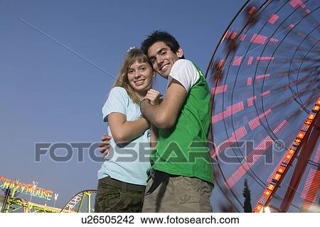 Teenage couple at Ferris wheel in amusement park View Large Photo Image Stock Image - Teenage couple at Ferris wheel in amusement park. Fotosearch