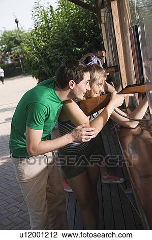 Stock Image - Teenage couple at game in amusement park. Fotosearch