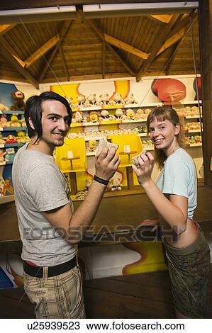 Teenage couple at game in amusement park View Large Photo Image Stock Image - Teenage couple at game in amusement park. Fotosearch