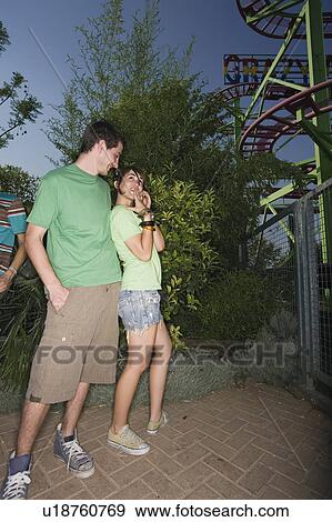 Stock Photo - Teenage couple at roller coaster in amusement park. Fotosearch