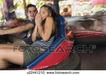Stock Image - Teenage couple in bumper car in amusement park. Fotosearch