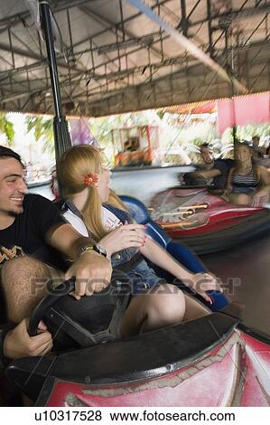 Stock Photo - Teenage couple in bumper car in amusement park. Fotosearch