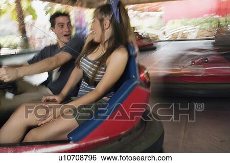 Stock Photograph - Teenage couple in bumper car in amusement park. Fotosearch
