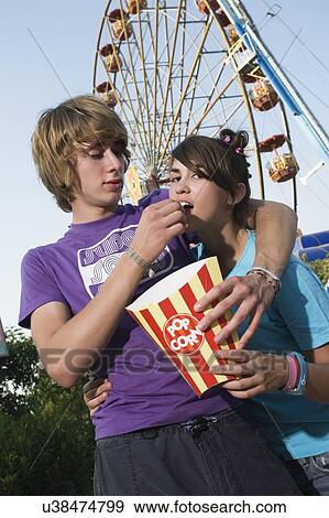 Teenage couple in front of Ferris wheel in amusement park View Large Photo Image Stock Photo - Teenage couple in front of Ferris wheel in amusement park. Fotosearch