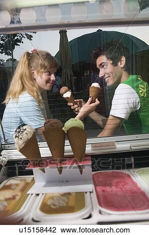 Stock Image - Teenage couple offering each other ice cream. Fotosearch