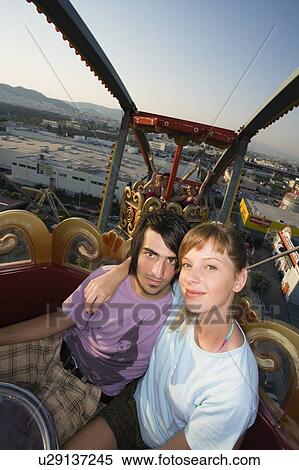 Teenage couple on Ferris wheel in amusement park View Large Photo Image Stock Photography - Teenage couple on Ferris wheel in amusement park. Fotosearch
