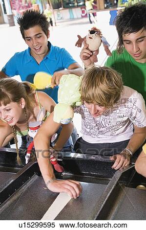 Stock Photography - Teenagers playing game in amusement park. Fotosearch