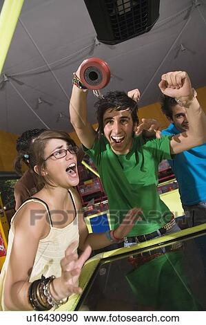 Stock Image - Teenagers playing game in arcade. Fotosearch