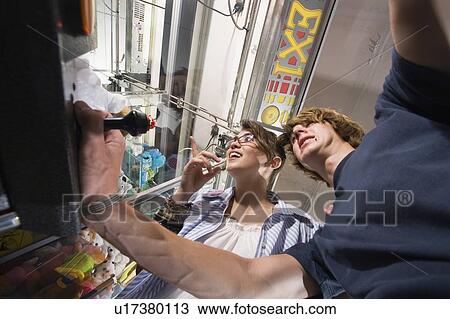 Teenagers playing game in arcade View Large Photo Image Stock Image - Teenagers playing game in arcade. Fotosearch
