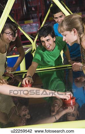 Stock Image - Teenagers playing game in arcade. Fotosearch