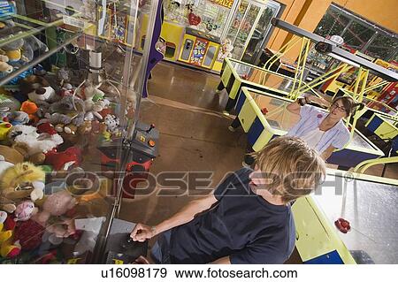 Teenagers playing game in arcade View Large Photo Image Stock Photo - Teenagers playing game in arcade. Fotosearch