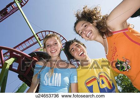 Teenagers posing at roller coaster at amusement park View Large Photo Image Stock Photograph - Teenagers posing at roller coaster at amusement park. Fotosearch