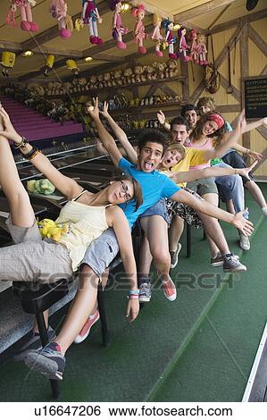 Stock Photograph - Teenagers posing in front of game in amusement park. Fotosearch