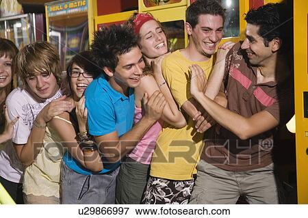 Stock Photo - Teenagers pushing on line in arcade. Fotosearch
