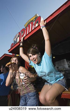 Stock Photo - Two female teenagers hanging out, eating pizza. Fotosearch