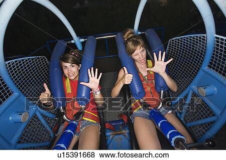 Stock Photo - Two female teenagers on amusement park ride. Fotosearch