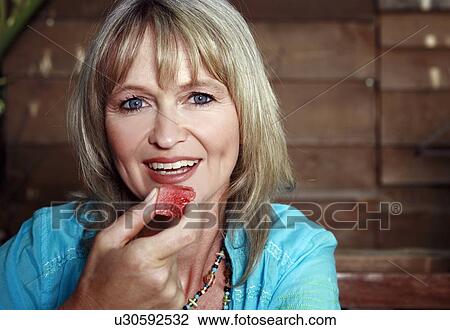 Stock Image - Female mature adult eating watermelon. Fotosearch