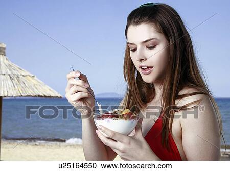 Female young adult eating fruit and yogurt on beach View Large Photo Image Stock Image - Female young adult eating fruit and yogurt on beach. Fotosearch