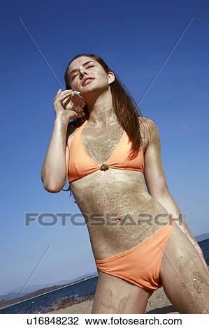 Female young adult in bikini listening to seashell View Large Photo Image Stock Image - Female young adult in bikini listening to seashell. Fotosearch
