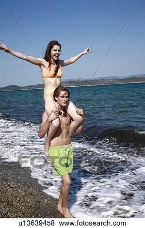 Female young adult riding on male young adult's shoulders View Large Photo Image Stock Photo - Female young adult riding on male young adult's shoulders. Fotosearch