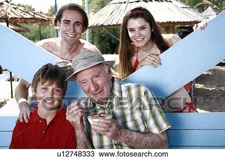 Grandfather, grandson, and young adult couple eating at beach View Large Photo Image Stock Image - Grandfather, grandson, and young adult couple eating at beach. Fotosearch