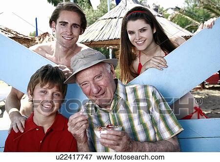 Grandfather, grandson, and young adult couple eating at beach View Large Photo Image Stock Photo - Grandfather, grandson, and young adult couple eating at beach. Fotosearch