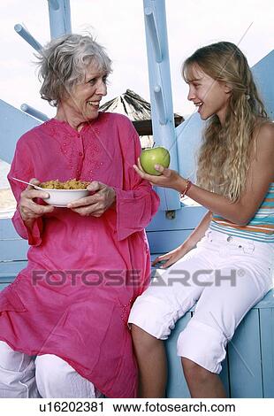 Grandmother and granddaughter eating at beach View Large Photo Image Stock Image - Grandmother and granddaughter eating at beach. Fotosearch
