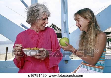 Grandmother and granddaughter eating at beach View Large Photo Image Stock Image - Grandmother and granddaughter eating at beach. Fotosearch