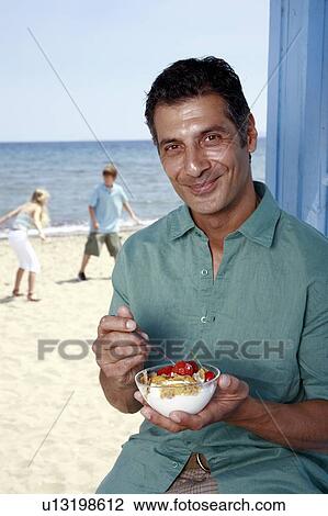 Male mature adult eating breakfast at beach View Large Photo Image Stock Image - Male mature adult eating breakfast at beach. Fotosearch