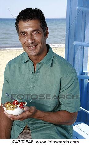 Male mature adult eating breakfast at beach View Large Photo Image Stock Photograph - Male mature adult eating breakfast at beach. Fotosearch
