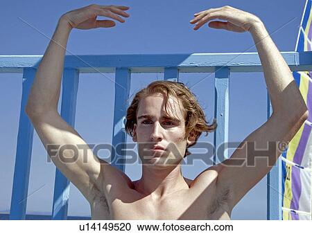 Stock Image - Male young adult doing yoga on beach. Fotosearch