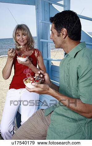Mature adult couple eating breakfast at beach View Large Photo Image Stock Photo - Mature adult couple eating breakfast at beach. Fotosearch