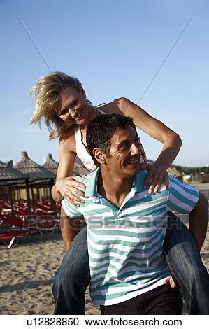 Mature adult couple piggyback on beach View Large Photo Image Stock Image - Mature adult couple piggyback on beach. Fotosearch