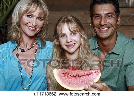 Stock Image - Parents with daughter and watermelon. Fotosearch