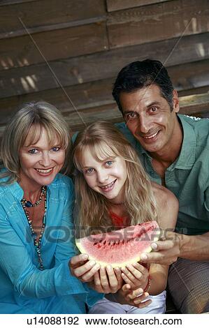 Stock Image - Parents with daughter and watermelon. Fotosearch