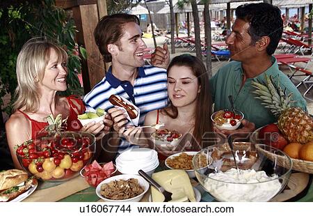 Young adult couple and parents eating breakfast View Large Photo Image Picture - Young adult couple and parents eating breakfast. Fotosearch