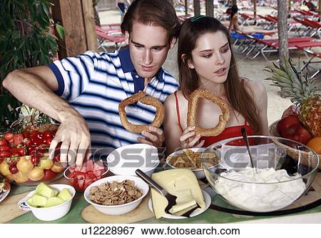 Young adult couple at breakfast holding sesame bread rings View Large Photo Image Stock Photo - Young adult couple at breakfast holding sesame bread rings. Fotosearch