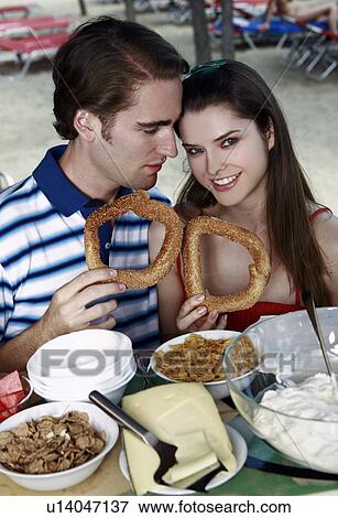 Young adult couple at breakfast holding sesame bread rings View Large Photo Image Stock Photo - Young adult couple at breakfast holding sesame bread rings. Fotosearch
