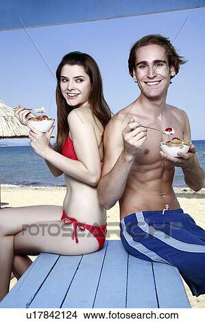Young adult couple eating breakfast on beach View Large Photo Image Picture - Young adult couple eating breakfast on beach. Fotosearch