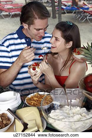 Young adult couple feeding each other breakfast View Large Photo Image Picture - Young adult couple feeding each other breakfast. Fotosearch