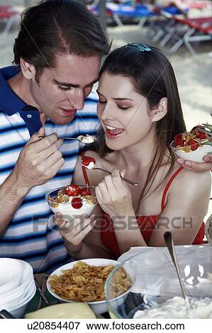 Young adult couple feeding each other breakfast View Large Photo Image Stock Photo - Young adult couple feeding each other breakfast. Fotosearch
