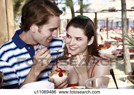Stock Photograph - Young adult couple feeding each other breakfast. Fotosearch