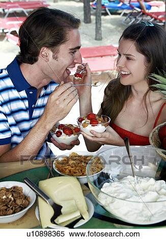Stock Photography - Young adult couple feeding each other breakfast. Fotosearch