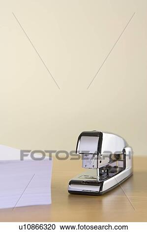 Stock Image - A Silver Stapler And A Pile Of Paperwork. Fotosearch