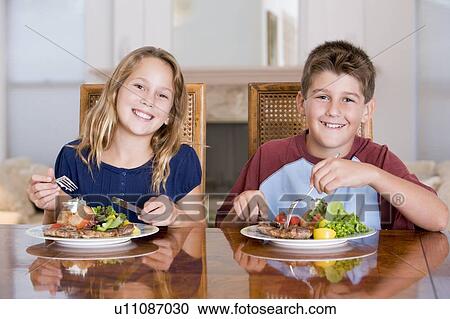 Stock Image - Brother And Sister Eating meal, mealtime Together . Fotosearch
