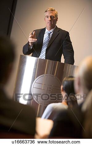 Businessman giving presentation at podium View Large Photo Image Stock Photograph - Businessman giving presentation at podium. Fotosearch
