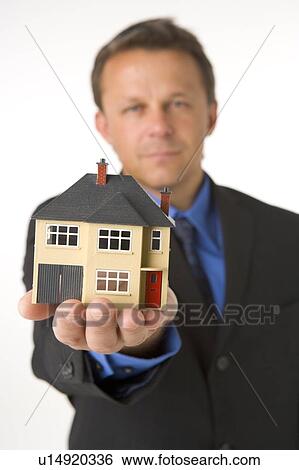 Stock Photograph - Businessman Holding Small House . Fotosearch