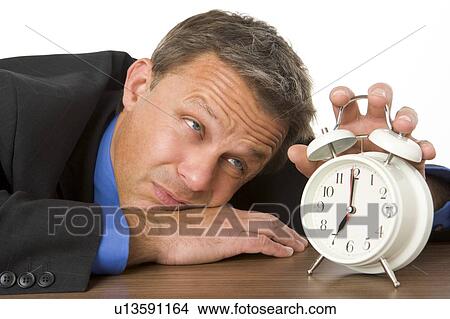 Picture - Businessman Leaning On Desk Watching Clock. Fotosearch