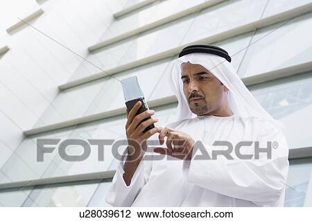 Businessman outdoors by building using PDA View Large Photo Image Stock Image - Businessman outdoors by building using PDA. Fotosearch
